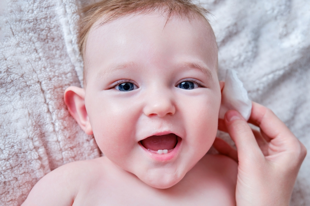Chườm nước nóng lên tai bé để hỗ trợ chữa nghẹt mũi cho trẻ sơ sinh